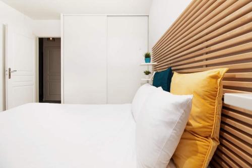 um quarto com uma cama com almofadas amarelas e brancas em Apt moderne & Confortable - Parking free em Toulouse