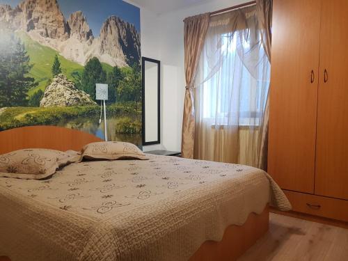 a bedroom with a bed and a painting on the wall at Apartament Silva Busteni in Buşteni