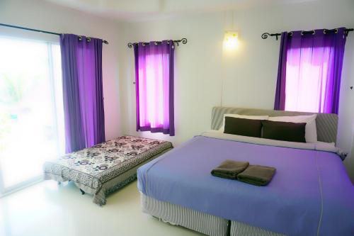 Schlafzimmer mit violetten Vorhängen und einem großen Bett in der Unterkunft Thongtalay Bed & Breakfast Koh Larn in Ko Larn