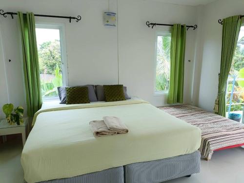 a bedroom with a large white bed with green curtains at Thongtalay Bed & Breakfast Koh Larn in Ko Larn