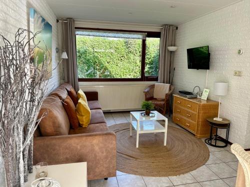 a living room with a couch and a table at Noordzeehuisje in Sint Maartensvlotbrug
