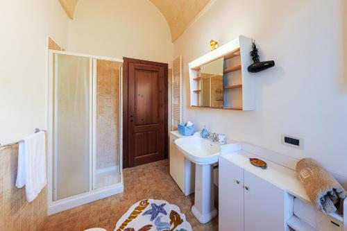 een witte badkamer met een wastafel en een spiegel bij HelloApulia Family Villa with Pool, Lush Garden & BBQ - Near the Beache in Savelletri di Fasano
