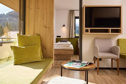a room with a bed and a tv and a table at Siplinger Suites - Ferienwohnungen - Sauna und Fitness in Balderschwang