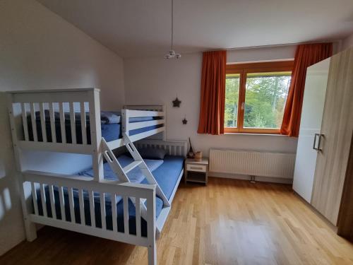a bedroom with two bunk beds and a window at Forest View Apartment in Pohorje