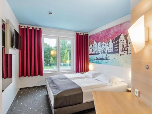 1 dormitorio con 1 cama y una ventana con cortinas rojas en B&B Hotel Lüneburg, en Lüneburg