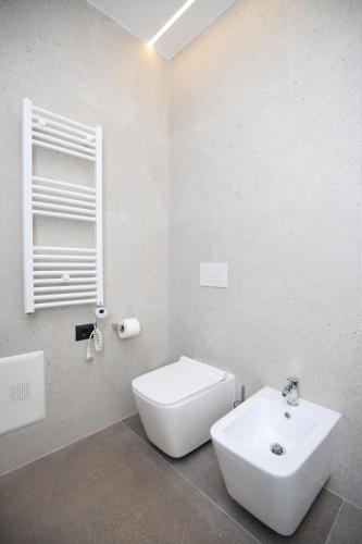 a white bathroom with a toilet and a sink at Charm Hotel in Vlorë