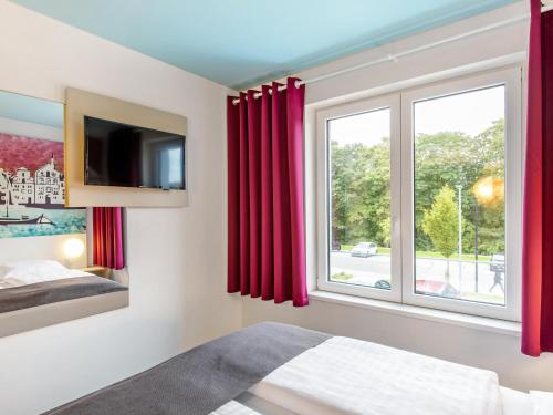- une chambre dotée d'une fenêtre avec des rideaux rouges dans l'établissement B&B Hotel Lüneburg, à Lunebourg