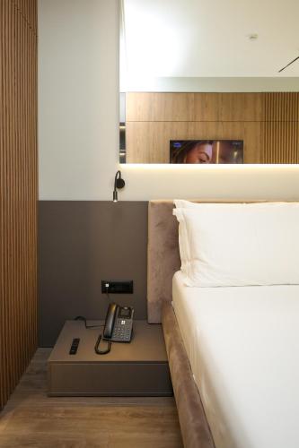 a bedroom with a bed with a phone on a night stand at Charm Hotel in Vlorë