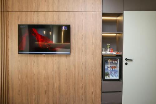 a television hanging on a wall with a refrigerator at Charm Hotel in Vlorë