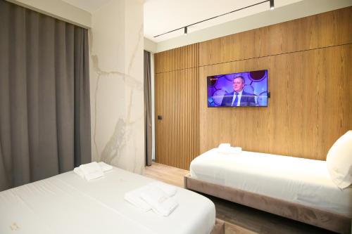 two beds in a room with a tv on a wall at Charm Hotel in Vlorë