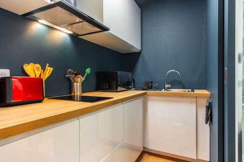 une cuisine avec des armoires blanches et un appareil rouge dans l'établissement Le Cocon de Claudie, à Nancy