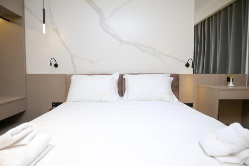 a bedroom with a large white bed with white pillows at Charm Hotel in Vlorë
