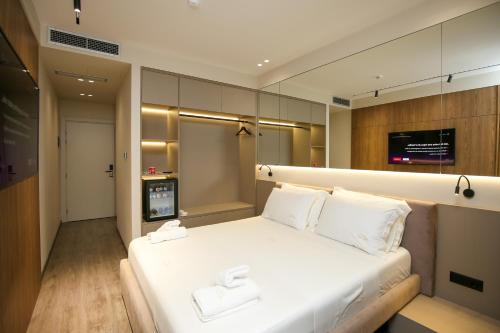 a bedroom with a large white bed with two white towels at Charm Hotel in Vlorë