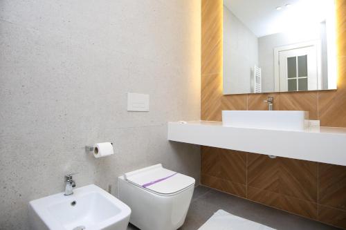 a white bathroom with a sink and a toilet at Charm Hotel in Vlorë