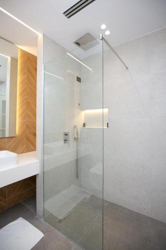 a glass shower in a bathroom with a sink at Charm Hotel in Vlorë