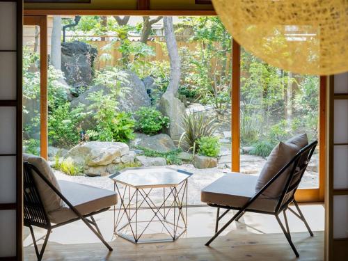 two chairs and a table in front of a garden at NIPPONIA Sawara Merchant Town Hotel in Katori