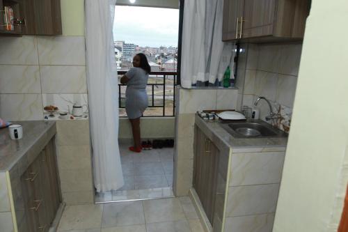 una donna in piedi in cucina che guarda fuori dalla finestra di Cherry home a Nairobi