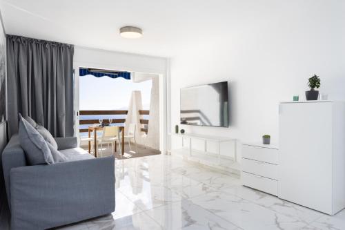 a white living room with a chair and a mirror at Home2Book Bright Studio Ocean View Tabaiba in Tabaiba