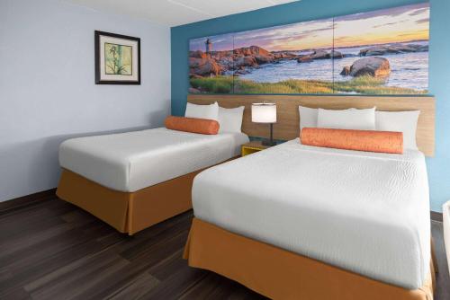 a hotel room with two beds and a painting on the wall at Days Inn by Wyndham Queensbury/Lake George in Queensbury