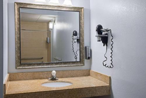 a bathroom with a sink with a mirror and a phone at Days Inn by Wyndham Queensbury/Lake George in Queensbury