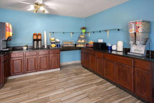 a large kitchen with wooden cabinets and blue walls at Days Inn by Wyndham Queensbury/Lake George in Queensbury