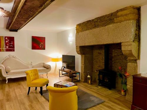 a living room with a stone fireplace and yellow chairs at Le Manoir des Haies in Les Champs-Géraux