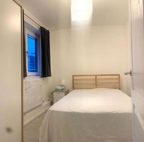 a white bedroom with a bed and a window at Lovely 12th floor 2 bed flat in the heart ofLondon in London