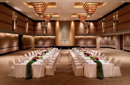 a row of tables in a banquet hall with white chairs at Grand Hyatt Jakarta in Jakarta