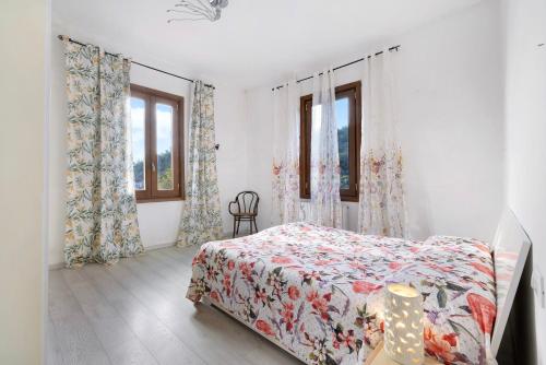 1 dormitorio con 1 cama con colcha de flores y 2 ventanas en La Casa di Ugo, en Loano