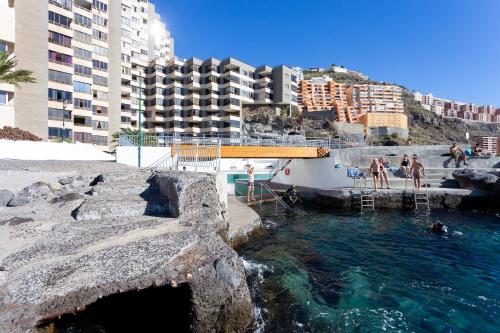 a swimming pool with people in the water and buildings at Home2Book Bright Studio Ocean View Tabaiba in Tabaiba