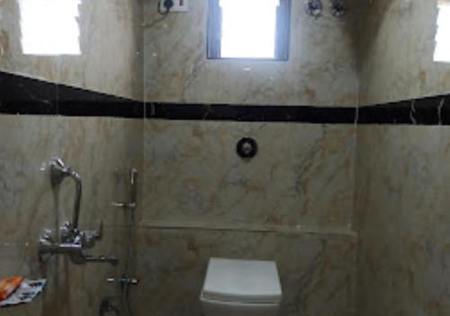 a bathroom with a toilet and a shower with a window at Hotel New Delhi darbar family restaurant Jalgaon in Jālgaon