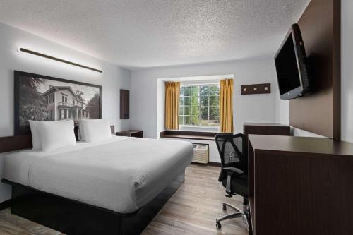 a hotel room with a bed and a desk and a television at Super 8 by Wyndham Harbison/Parkridge Hospital in Columbia
