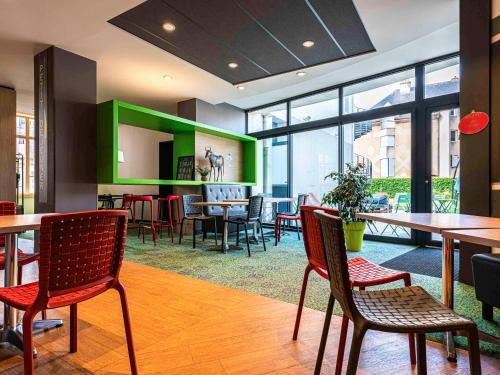 un restaurant avec des tables et des chaises et un mur vert dans l'établissement ibis Styles Moulins Centre, à Moulins