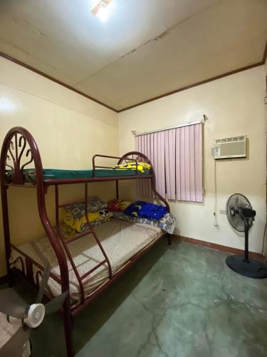 Perucho-Silang Guest House في مابيني: غرفة بسريرين بطابقين ومروحة