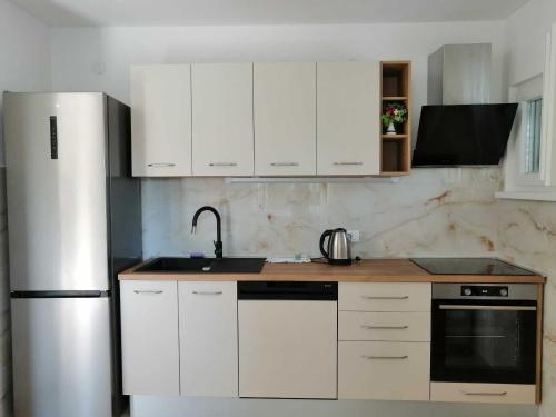 a kitchen with white cabinets and a stainless steel refrigerator at Apartments and rooms Porto in Ražanj