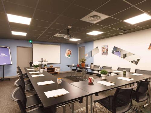 a conference room with tables and chairs and a screen at Greet Hotel Lyon Confluence in Lyon