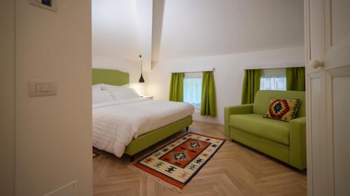 a bedroom with a bed and a green chair at B&B PIEDICASTELLO in Trento