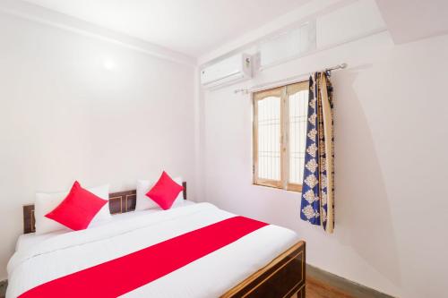 a bedroom with a bed with red pillows and a window at Super OYO New Suhani House in Rāmnagar