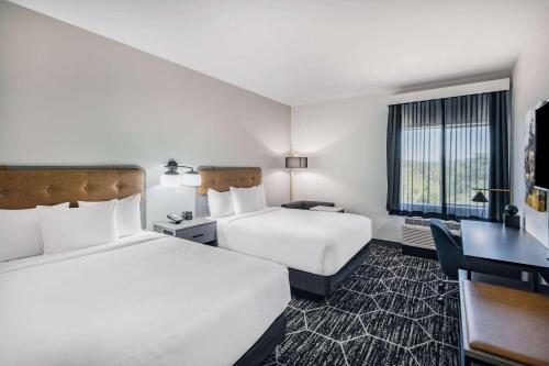 a hotel room with two beds and a desk at La Quinta Inn & Suites by Wyndham Yucaipa 