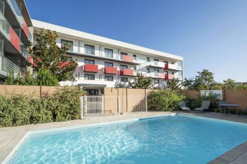 uma piscina em frente a um edifício em Best Western Les Aureliades Saint Nazaire em Trignac