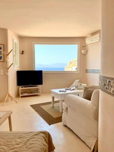a living room with a couch and a flat screen tv at Marialena's studio in Agios Ioannis Mykonos