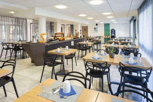 a restaurant with wooden tables and chairs and a counter at Best Western Les Aureliades Saint Nazaire in Trignac