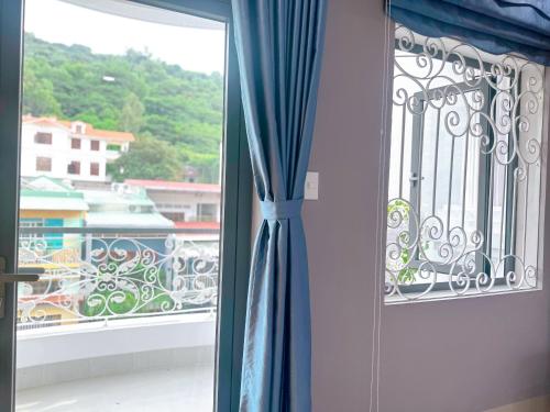 a window with blue curtains and a view of a balcony at Milanesa Hotel and Apartment in Vung Tau