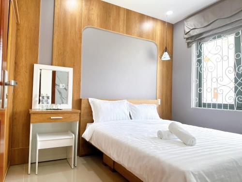 a bedroom with a bed and a mirror and a window at Milanesa Hotel and Apartment in Vung Tau