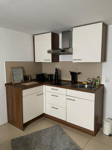 a kitchen with white cabinets and a sink at Appartment Schmidtner in Ansbach