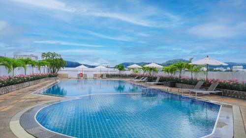a swimming pool with chairs and umbrellas at a resort at Royal Phuket City Hotel - SHA Extra Plus in Phuket Town