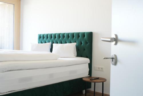 a bed with a green headboard in a room at Aparthouse Leonhard in Feldkirch