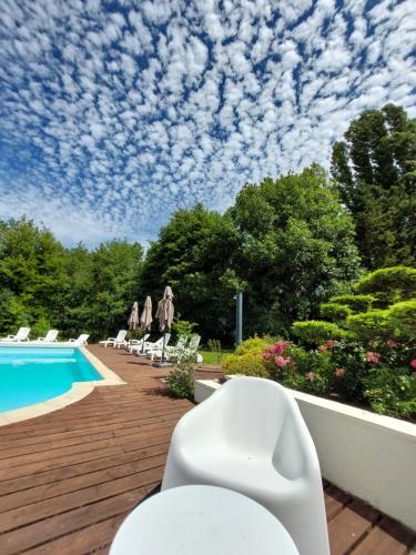 une terrasse avec une piscine, des chaises et un ciel nuageux. dans l'établissement Traînefeuilles - Gîte au Four à Pain proche Zoo de Beauval, à Thenay