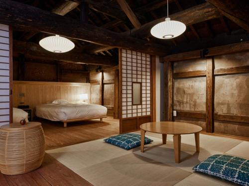 a bedroom with a bed and a table at NIPPONIA Sawara Merchant Town Hotel in Katori