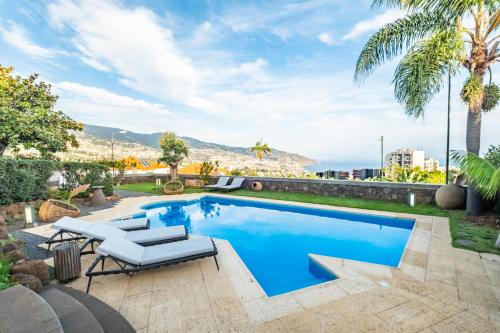 a swimming pool with two lounge chairs and a villa at Villa Magnólia in Funchal